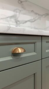 detail shot of kitchen hardware. close up of sage green cabinet drawer with brushed brass pull
