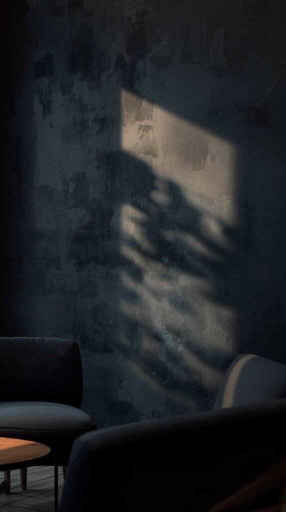 Moody dark limewashed accent wall in inky navy, dramatic tonal movement, warm accent lighting grazing the wall, modern furniture