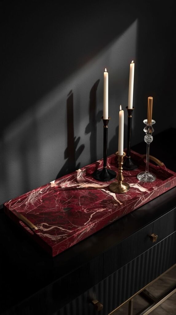 Moody interior vignette with a red marble tray placed on a dark wood or black console table, deep burgundy and wine-toned veining.
