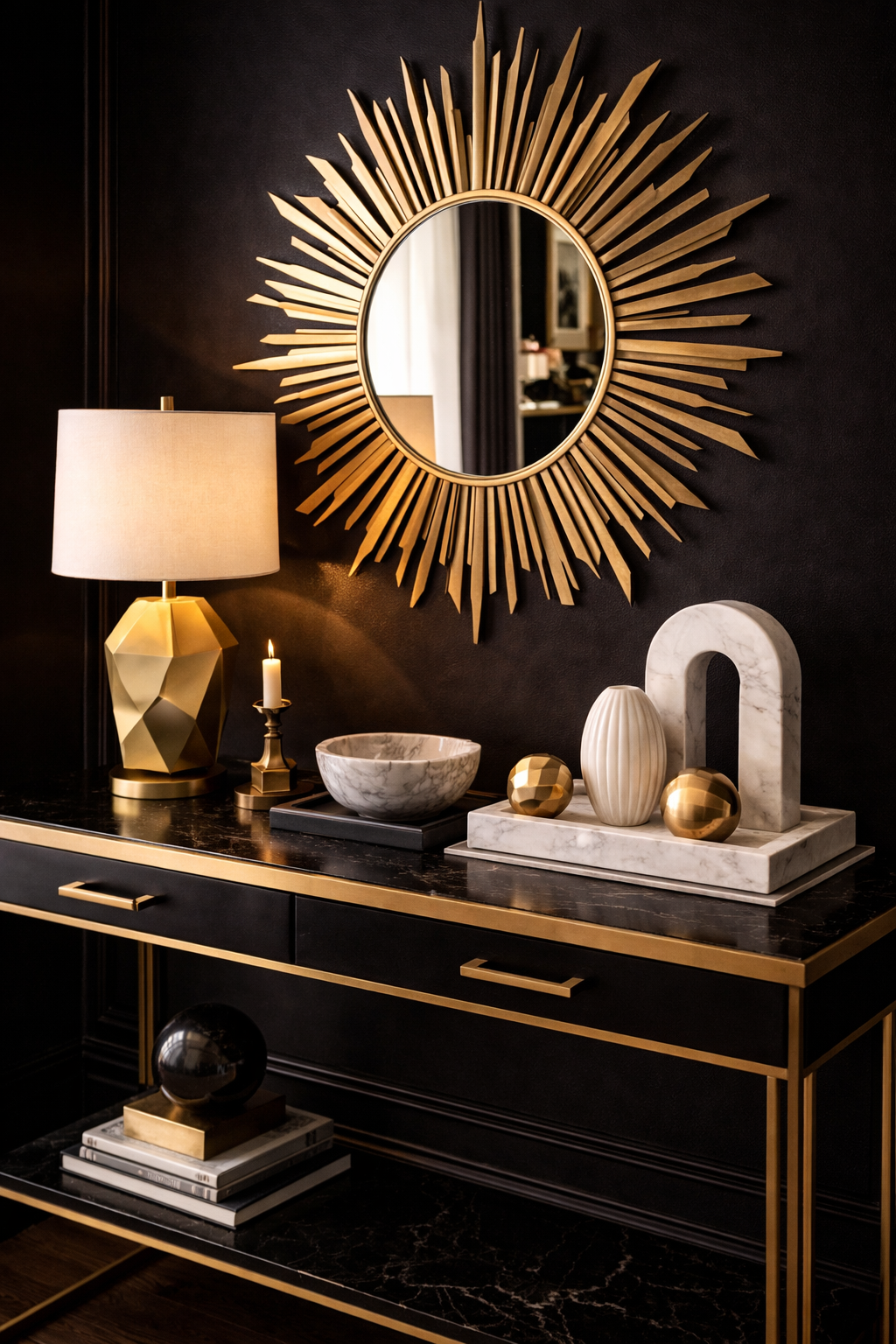 Neo-Deco entryway console with a sunburst mirror, brass lamp, marble tray, and sculptural objects in dramatic black and gold styling
